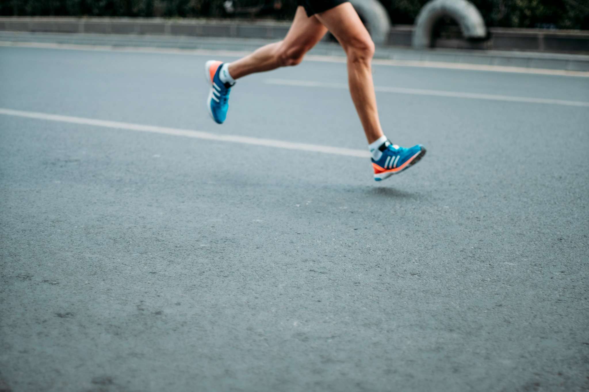 Runner on road wearing blue trainers Runner on road wearing blue trainers